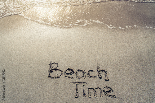 Beach time hand drawn lettering text on sand. Sunburst