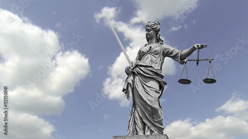 Statue of Lady Justice in front of moving clouds