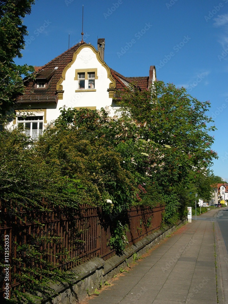 Weiße Villa aus der Gründerzeit mit Garten vor azurblauem Himmel bei