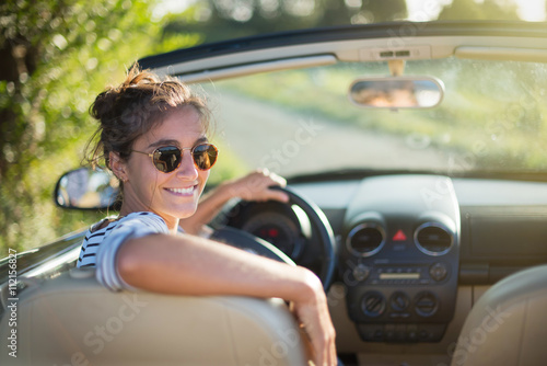 Schilderij op canvas Rear view. A young woman happy to drive her convertible car