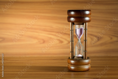 vintage hourglass on vintage brown wood table background