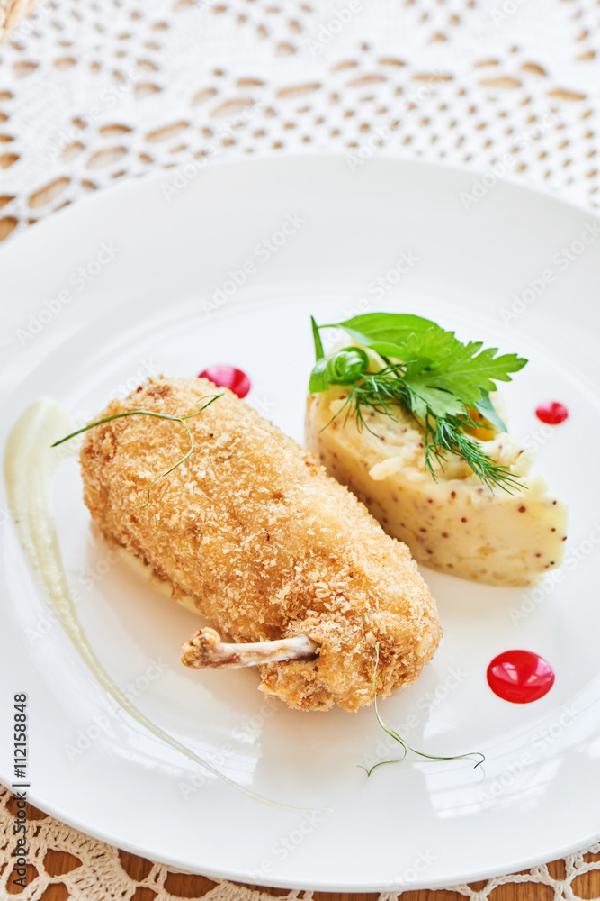 Chicken Kiev fried in breadcrumbs, Parmesan sauce and mashed potatoes with Dijon mustard served on a white plate