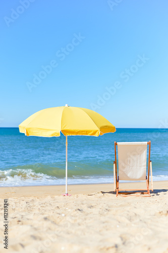 Back View Of Deckchair  Sun Lounger Under Umbrella On Sand Beach. 