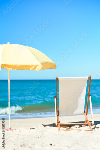 Fototapeta Naklejka Na Ścianę i Meble -  Yellow umbrella and wooden chair on Atlantic sandy beach