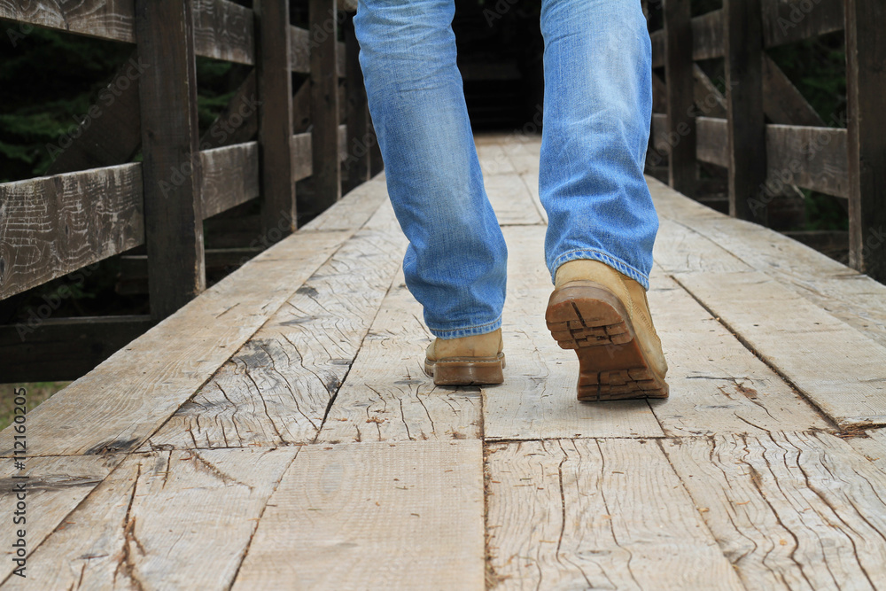 Man wearing lumberjack boots walking on old wooden bridge close up. Hunter fisherman Adventure man style. Travel, Wanderlust concept. - obrazy, fototapety, plakaty 