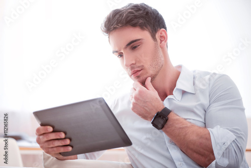Thoughtful handsome man using tablet 