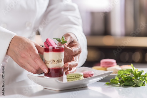 Fototapeta Naklejka Na Ścianę i Meble -  closeup on hands of a pastry chef depositing a mint leaf