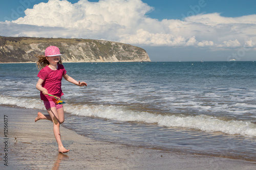 Little girl running along the shore of an English beach photo
