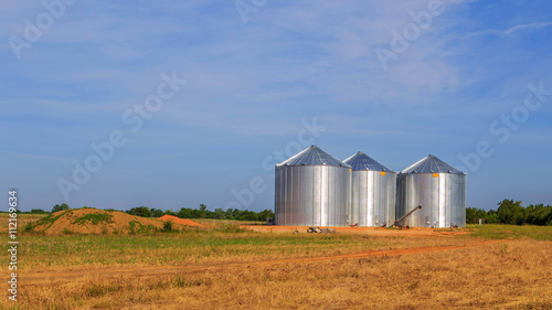 Triple Stainless Steel Grain Silo:
Three adjacent stainless steel silos in an open field just off highway 80 in Demopolis, AL   photo
