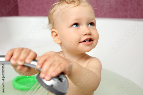 Cute baby boy taking shower in bathroom
