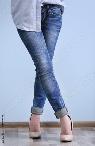 Beautiful young woman in shirt and jeans on blue wall background