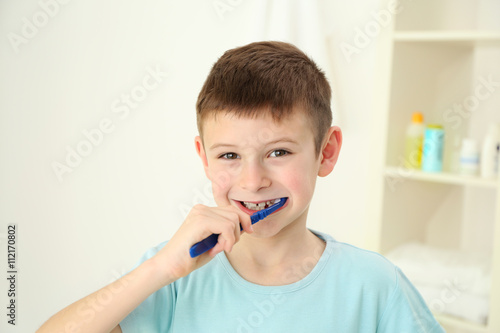 Smiling little boy brushing teeth, close up
