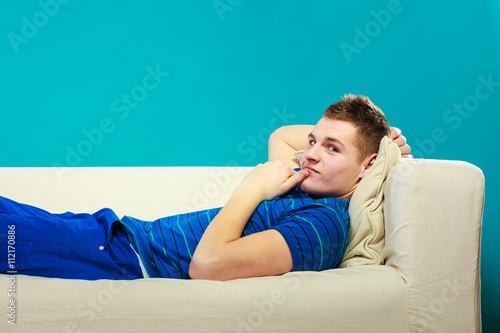 Young man relaxing on couch on blue © Voyagerix