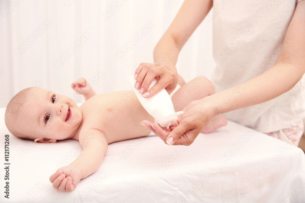 Mother hands changing diaper to little baby in room