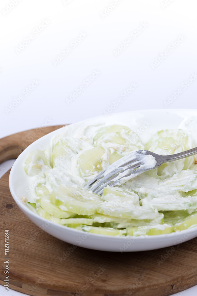 Fork in cucumbers salad with onions and sour cream Fork in cucumbers salad with onions and sour cream