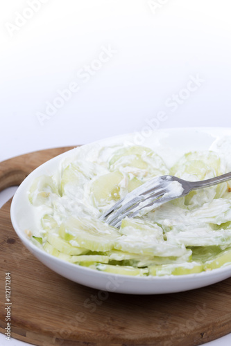 Fork in cucumbers salad with onions and sour cream