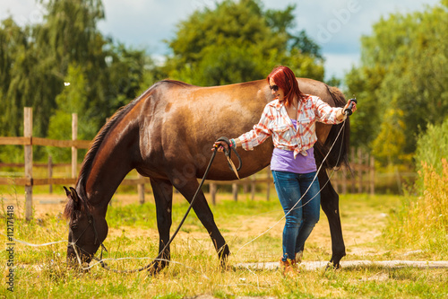 Young woman girl taking care of horse.