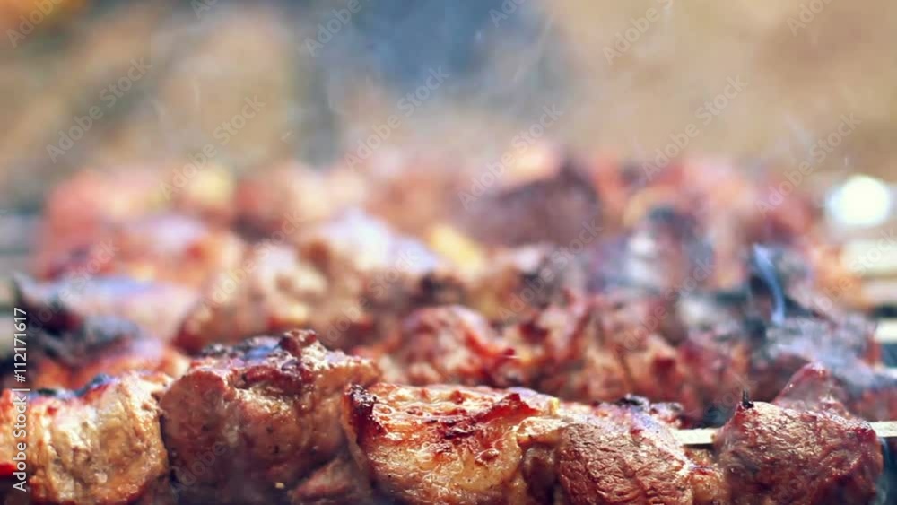 Grilling barbecue meat on wood coal. Man turns skewers. Man cooks appetizing hot shish kebab on metal skewers. Tasty meat pieces with crust. Grilling food. Cooking shashlik on barbecue grill. Closeup Grilling barbecue meat on wood coal. Man turns skewers. Man cooks appetizing hot shish kebab on metal skewers. Tasty meat pieces with crust. Grilling food. Cooking shashlik on barbecue grill. Closeup