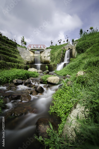 beautiful scenery of hidden waterfall with cloudy sky in the middle of tea farm at Cameron Highland, Malaysia.Soft focus and some motion blur due to long exposure. Focus in the center