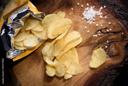 Snack of potato chips with sea salt over wooden background. Top view.