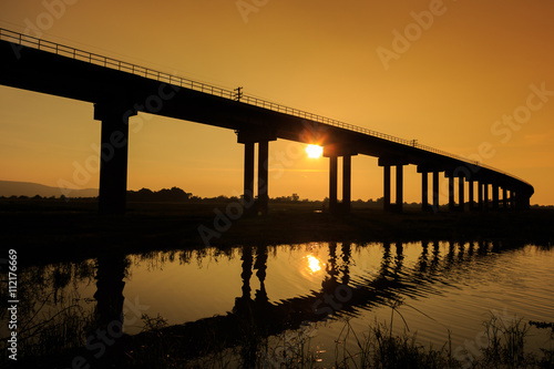 Fototapeta Naklejka Na Ścianę i Meble -  A train is crossing bridge at  Pa Sak Jolasid Dam, Thailand in sunset time