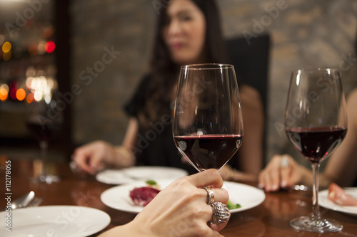 Young women are enjoying the meal with a glass of wine