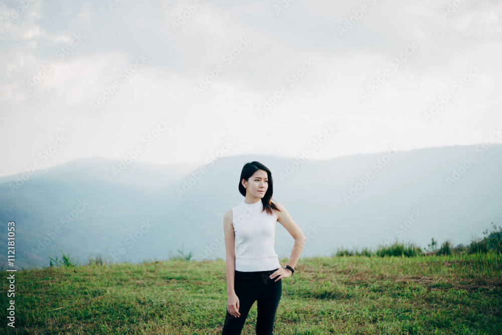 Smile Asian girl standing on meadow with mountainous background.