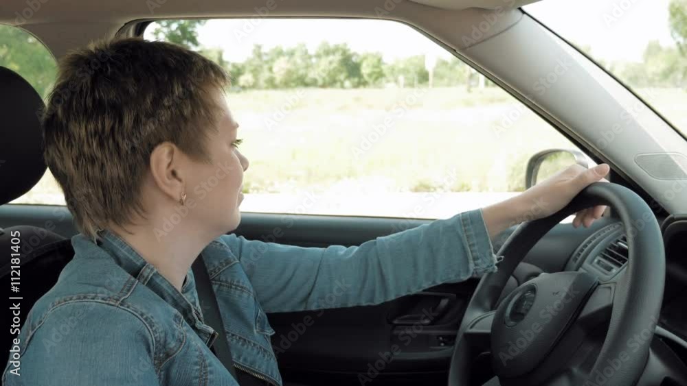 Pretty blond short hair woman sets out and drives a car on city streets. POV from inside the car cabin urban traffic scene. 4K UHD video footage. Pretty blond short hair woman sets out and drives a car on city streets. POV from inside the car cabin urban traffic scene. 4K UHD video footage.