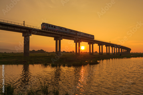 Fototapeta Naklejka Na Ścianę i Meble -  A train is crossing bridge at  Pa Sak Jolasid Dam, Thailand in sunset time