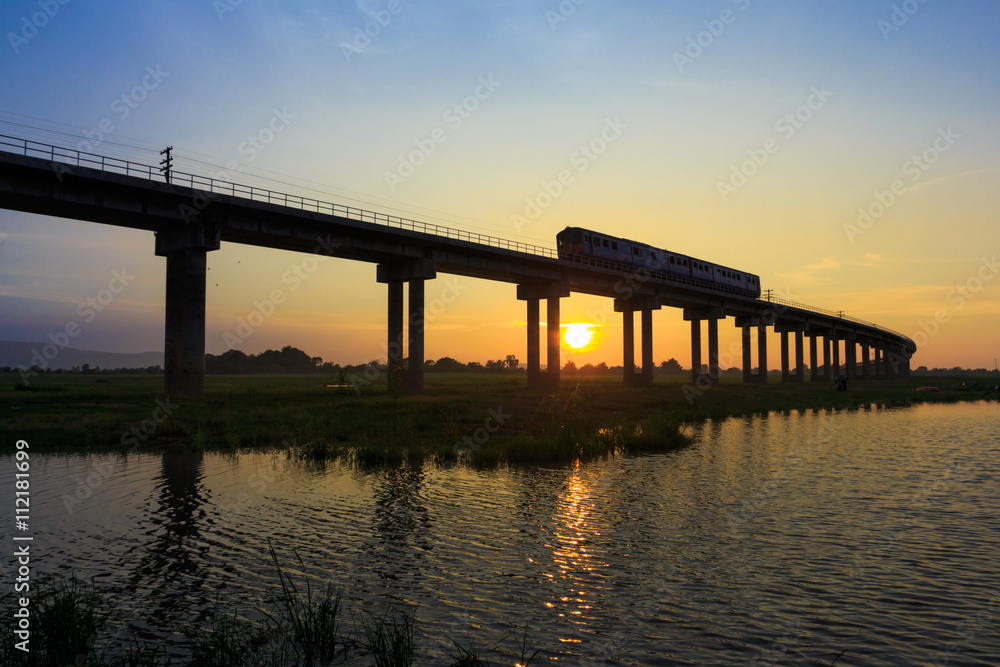 A train is crossing bridge at Pa Sak Jolasid Dam, Thailand in sunset time A train is crossing bridge at Pa Sak Jolasid Dam, Thailand in sunset time