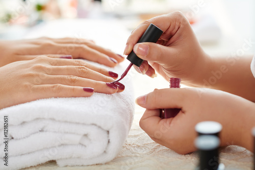 Valokuvatapetti Side view of manicurist applying marsala nail polish