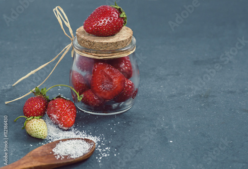 strawberries in a jar tied with a ribbon sugar and wooden spoon