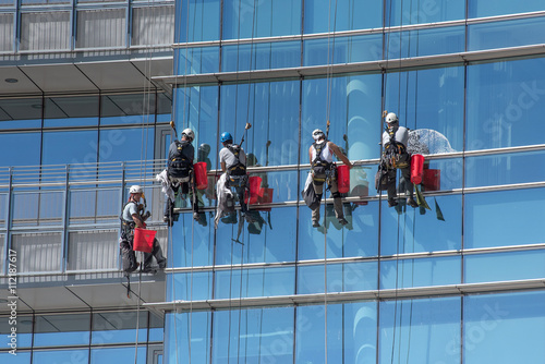 Group of window cleaners suspended from cables photo