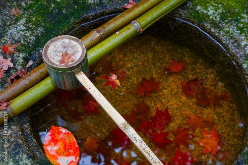 Water dipper with a stone basin ina a Japanese garden in autumn photo