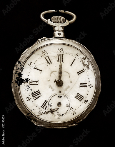 Antique silver broken pocket watch isolated on a pure black background, top view, HDR processing in old style.