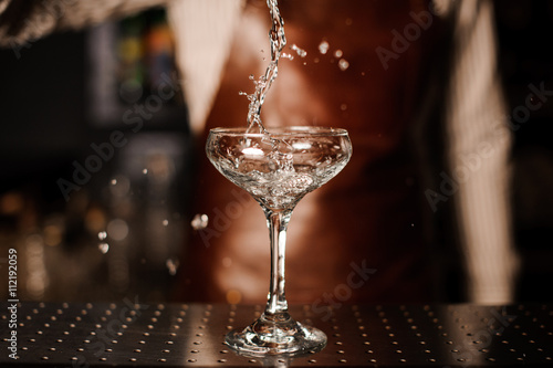 Barman pouring into champagne glass and making a splash