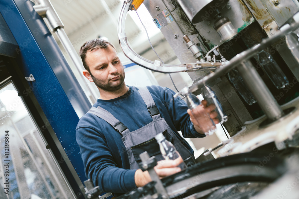 Serious manual worker doing his job on factory production line for water purification and bottling. Serious manual worker doing his job on factory production line for water purification and bottling.