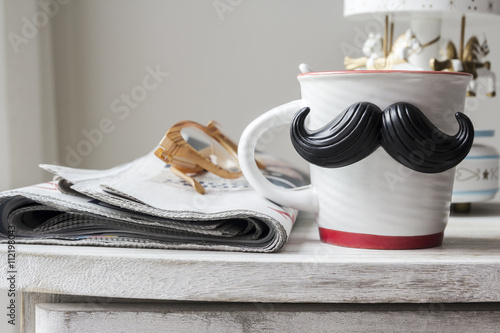 Cup with mustache on vintage cabinet for fathers day concept photo