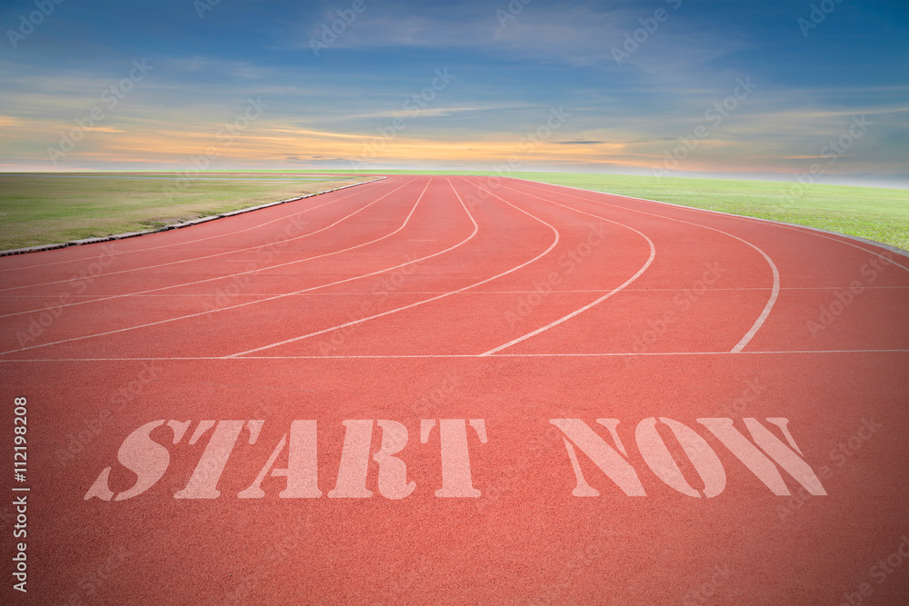 Obraz premium Start now written on Running track with green grass and blue sky