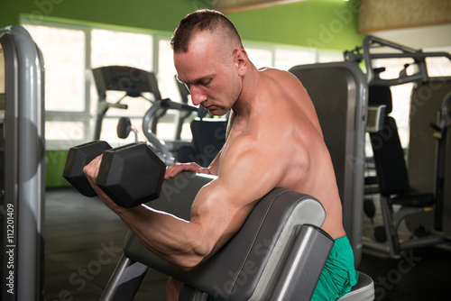 Young Man Doing Exercise For Biceps With Dumbbells