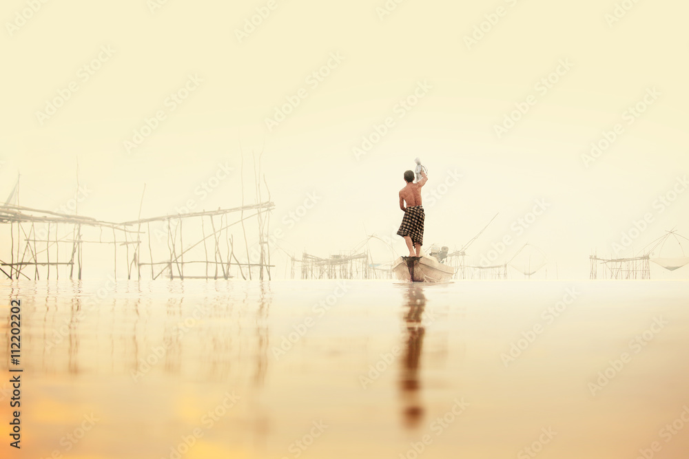 Naklejka premium Fishermen on boat fishing with a large fishnet.Silhouette scene of the morning.