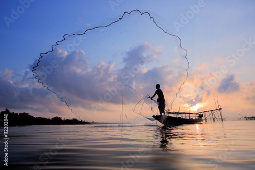 Fotografie Fishermen on boat fishing with a fishnet,the old traditional equipment of Thai fishery