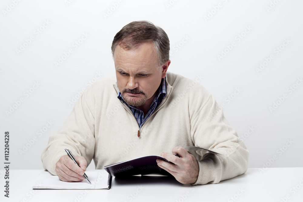 mature businessman making notes from a magazine. mature businessman making notes from a magazine.