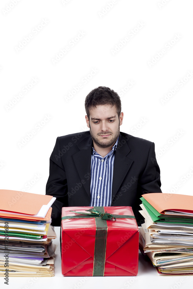 businessman looking at gift and files on his desk. businessman looking at gift and files on his desk.