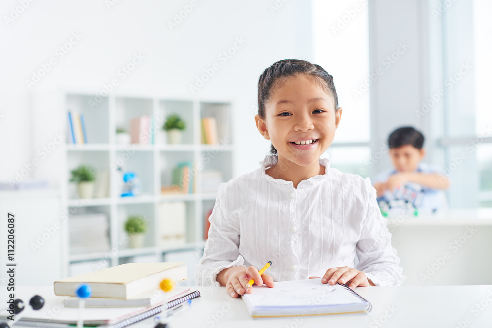 Portrait of cute Vietnamese schoolgirl sitting at her desk Portrait of cute Vietnamese schoolgirl sitting at her desk