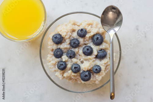 Bowl of oatmeal porridge with blueberry on marble table