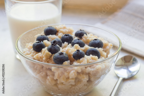 Bowl of oatmeal porridge with blueberry on marble table