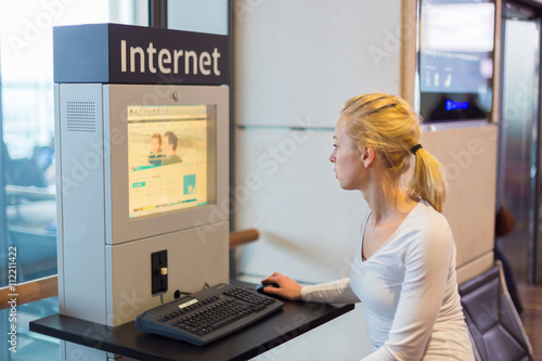 Young caucasian woman using comupter with public internet access point on airport. photo