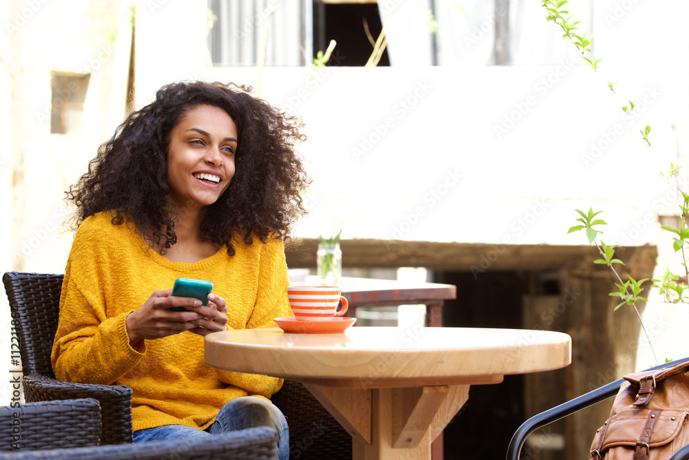 Cheerful young african woman sitting at outdoor cafe