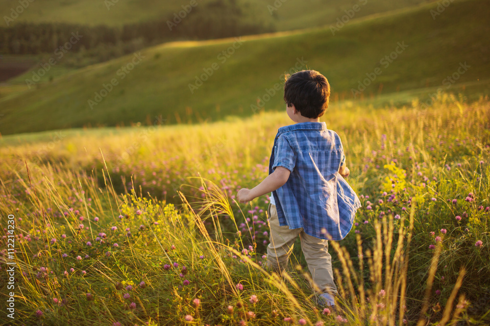 A little boy goes down on a hill at the sunset A little boy goes down on a hill at the sunset